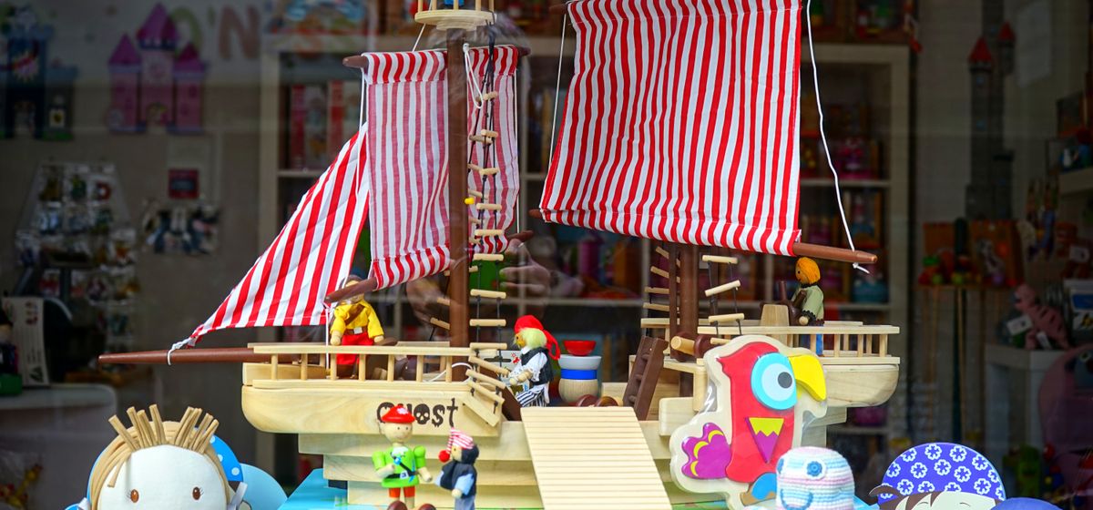 Vitrine de loja de brinquedos com barco de madeira e bichos de pelúcia coloridos